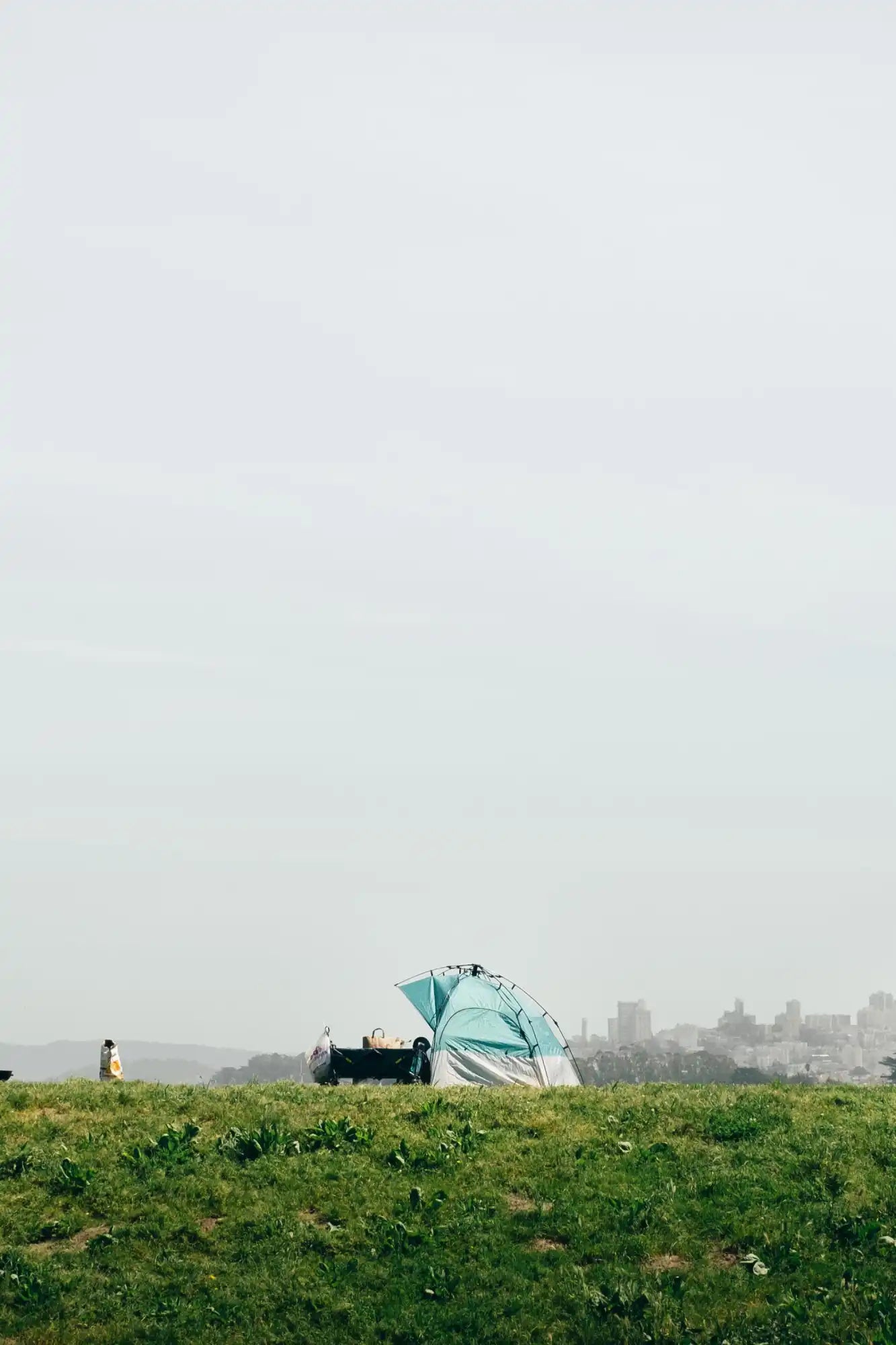 Teal camping tent pitched on grassy terrain.